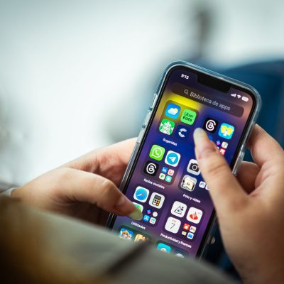 Mulher segura um smartphone que exibe diversos aplicativos na tela.