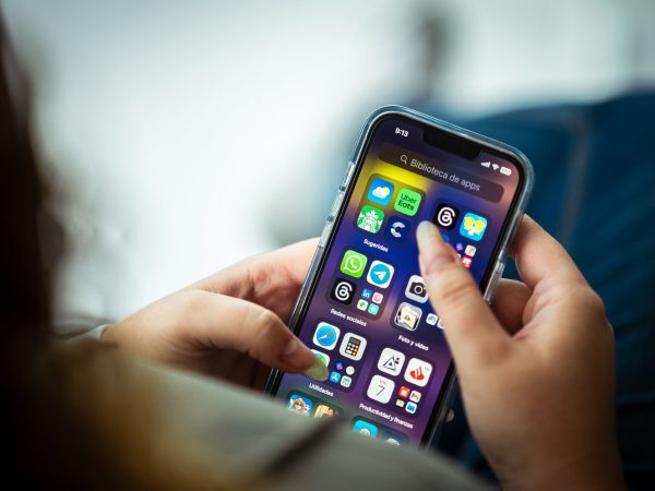 Mulher segura um smartphone que exibe diversos aplicativos na tela.