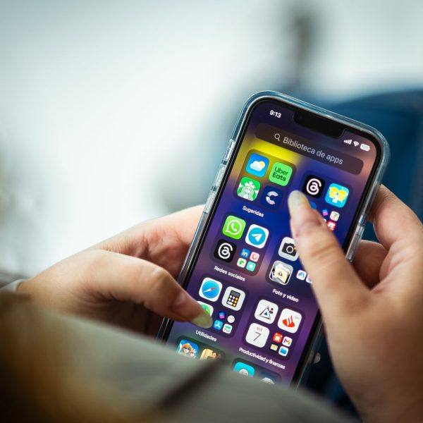 Mulher segura um smartphone que exibe diversos aplicativos na tela.