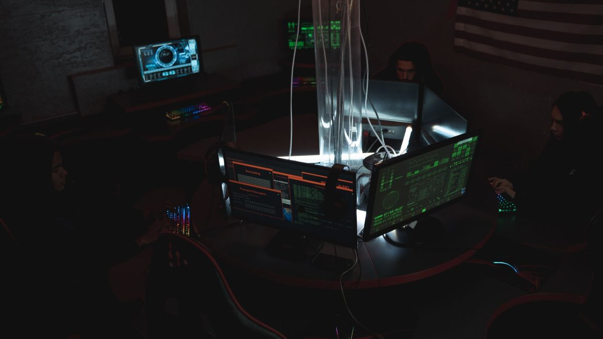 Equipe de especialistas em cibersegurança trabalhando diante de computadores em uma sala pouco iluminada.