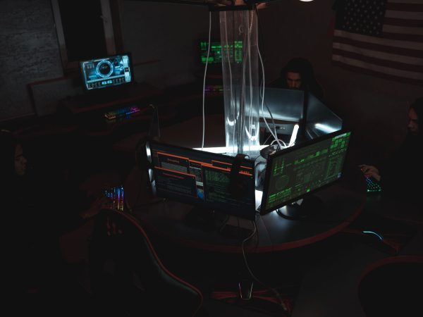 Equipe de especialistas em cibersegurança trabalhando diante de computadores em uma sala pouco iluminada.