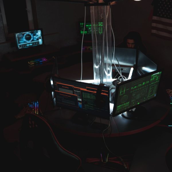 Equipe de especialistas em cibersegurança trabalhando diante de computadores em uma sala pouco iluminada.
