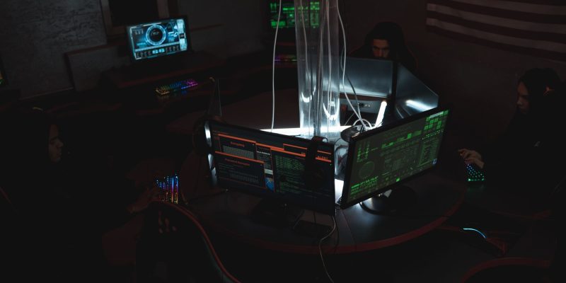 Equipe de especialistas em cibersegurança trabalhando diante de computadores em uma sala pouco iluminada.
