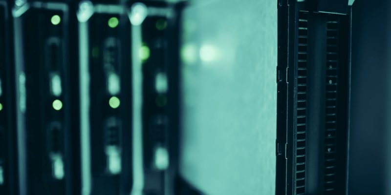 Racks de servidores iluminados em azul em um data center, representando infraestrutura de computação de alto desempenho.