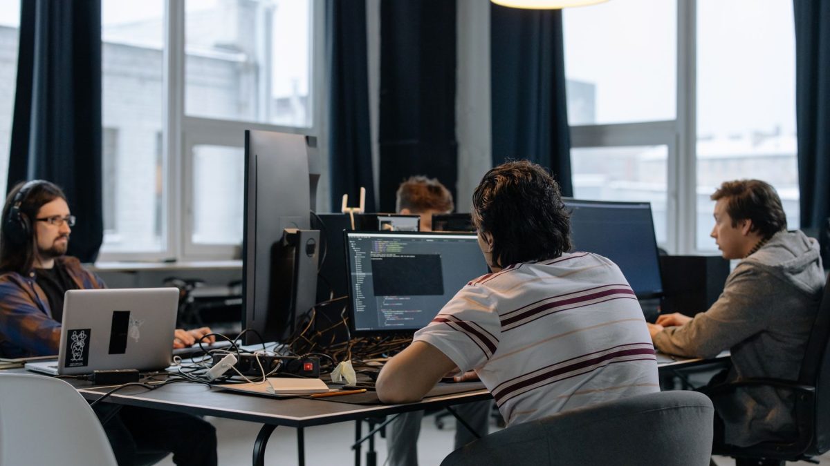 Equipe de desenvolvedores trabalha em computadores em um escritório de tecnologia.