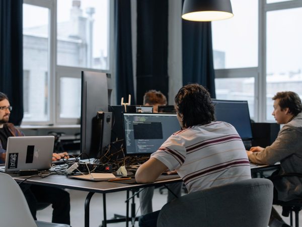 Equipe de desenvolvedores trabalha em computadores em um escritório de tecnologia.