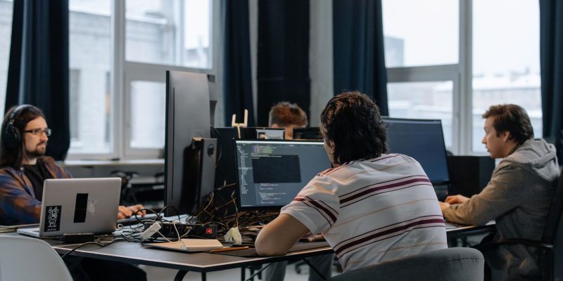 Equipe de desenvolvedores trabalha em computadores em um escritório de tecnologia.