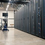 Fileiras de gabinetes metálicos com servidores, equipamentos de rede e cabos em um data center moderno