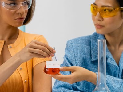 Duas cientistas seguram um frasco em um laboratório durante uma atividade de pesquisa.