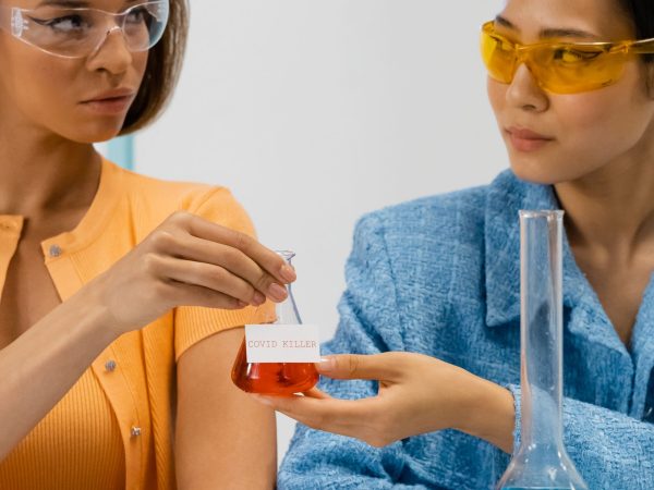 Duas cientistas seguram um frasco em um laboratório durante uma atividade de pesquisa.