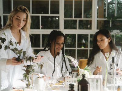 Três mulheres cientistas examinam plantas em um laboratório.