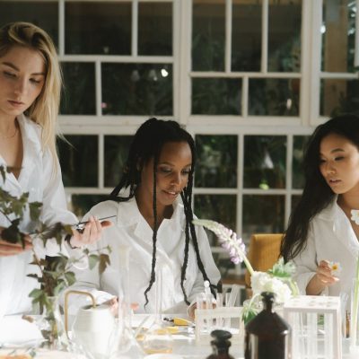 Três mulheres cientistas examinam plantas em um laboratório.