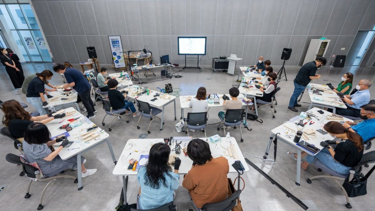 Estudantes participam de uma atividade prática com equipamentos tecnológicos em uma sala de aula.
