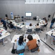 Estudantes participam de uma atividade prática com equipamentos tecnológicos em uma sala de aula.