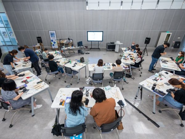 Estudantes participam de uma atividade prática com equipamentos tecnológicos em uma sala de aula.