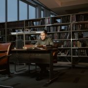 Pesquisador estuda concentrado em uma biblioteca cercado por livros.