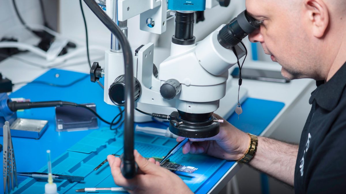 Técnico examina um chip sob microscópio em um laboratório de pesquisa.