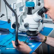 Técnico examina um chip sob microscópio em um laboratório de pesquisa.
