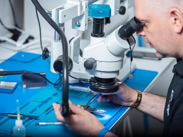 Técnico examina um chip sob microscópio em um laboratório de pesquisa.