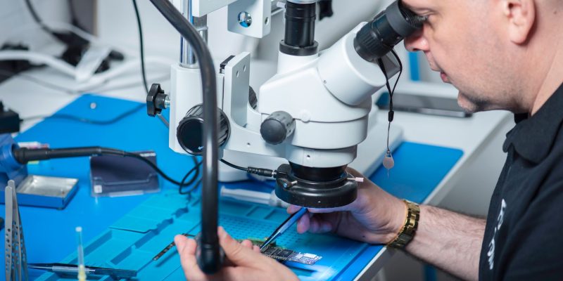 Técnico examina um chip sob microscópio em um laboratório de pesquisa.