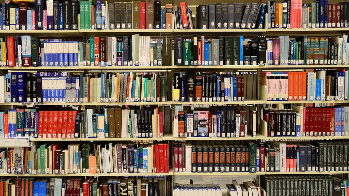 Estantes repletas de livros em uma biblioteca, representando pesquisa e produção de conhecimento.