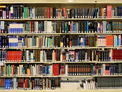 Estantes repletas de livros em uma biblioteca, representando pesquisa e produção de conhecimento.