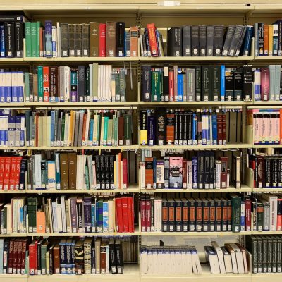 Estantes repletas de livros em uma biblioteca, representando pesquisa e produção de conhecimento.