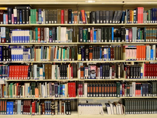 Estantes repletas de livros em uma biblioteca, representando pesquisa e produção de conhecimento.