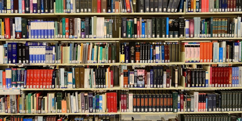 Estantes repletas de livros em uma biblioteca, representando pesquisa e produção de conhecimento.